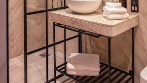 Ein modernes Badezimmer mit Glasabtrennung, Marmorwaschbecken und Duschbereich.