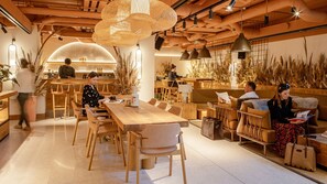 A modern interior with a wooden dining area, bar, and seating with plants. - Wren Urban Nest (Dublin)
