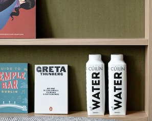 A shelf with a book titled 'Guide to Temple Bar Dublin', a book titled 'Greta Thunberg', and two bottles labeled 'Cúilín Water'. - Wren Urban Nest (Dublin)