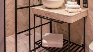 Un bagno moderno con cabina doccia separata da un vetro, lavabo in marmo e area doccia.