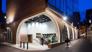 A modern building with a large arched entrance, a staircase leading to an upper level, and a sign that reads "Wiener". - Wren Urban Nest (Dublin)
