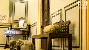 A room with a wooden bench, a mirror, and two elephant statues. - The Umaid Vilas Royal Heritage Haveli (Jaipur)