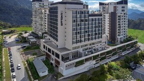 Un hotel moderno de varios pisos con un patio central, rodeado de exuberante vegetación y montañas al fondo.