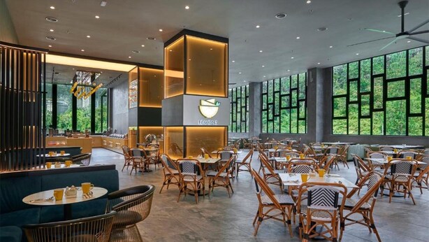 Un restaurante espacioso con techos altos, ventanas amplias y diversas opciones de asientos, incluyendo mesas y sillas.
