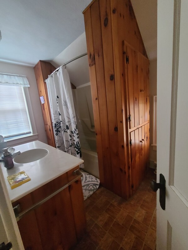 Une salle de bain avec un meuble-lavabo en bois, un évier et un espace douche.