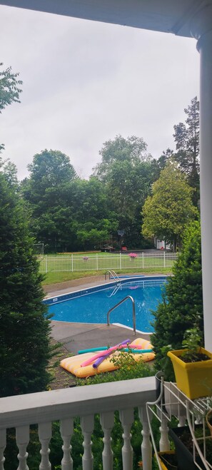 A swimming pool with a white fence and trees in the background. - Joyful Manor  (Norwich)