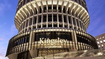 A modern hotel with a circular facade, a prominent Kingsley Crystalbrook sign, and a glass entrance.