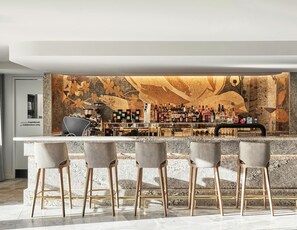 A modern bar area with a stone wall mural, bar stools, and a variety of liquor bottles. - Crystalbrook Kingsley (Newcastle)