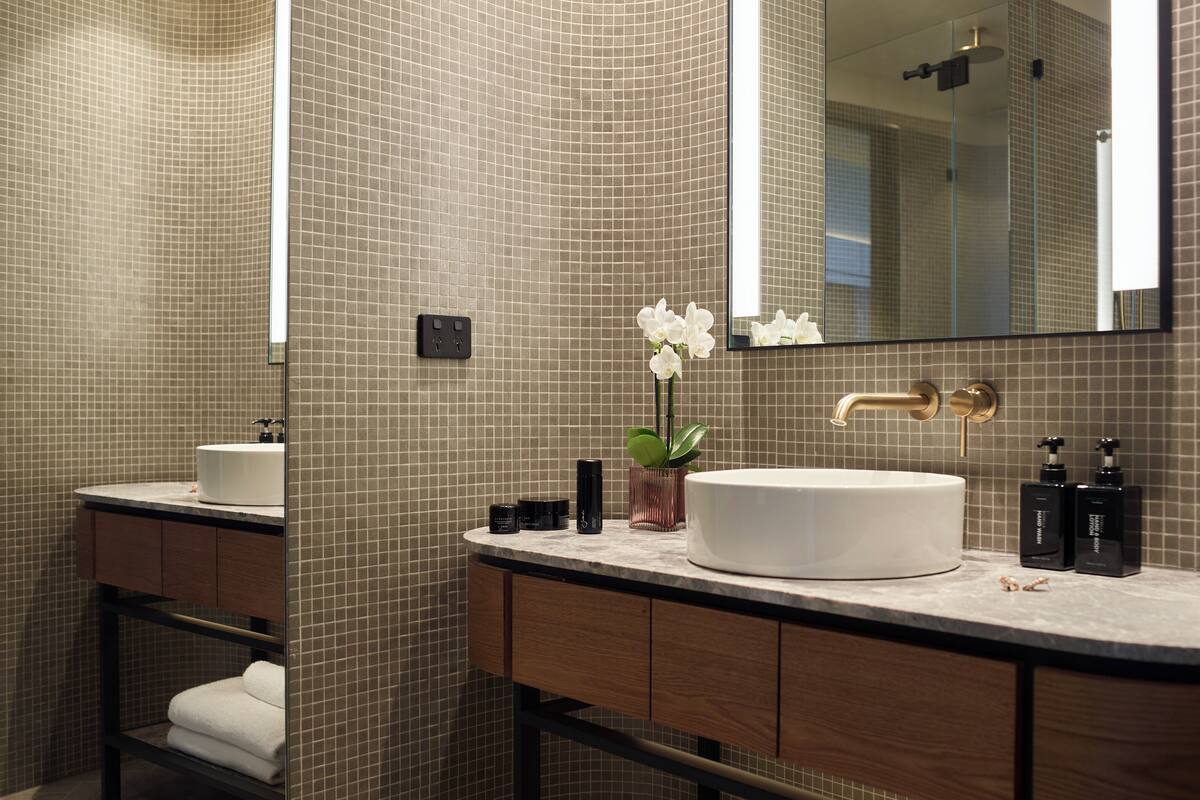 Un bagno moderno con uno specchio grande, due lavabi e un mobile contenitore con porta asciugamani.