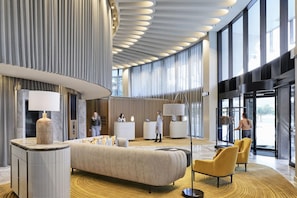 Un hall d'entrée moderne doté d'un grand lit, d'un coin salon, d'un comptoir d'accueil et de grandes fenêtres.