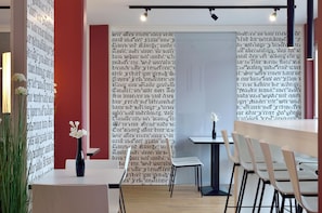 A modern interior with a white table, chairs, and a vase with white flowers. - B&B Hotel München Messe Dornach (Aschheim)