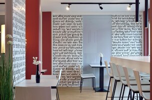 Un interior moderno con una mesa blanca, sillas y un jarrón con flores blancas.