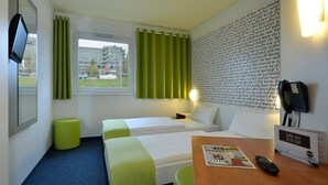 Una habitación de hotel con dos camas, un escritorio, un teléfono y una ventana con cortinas.