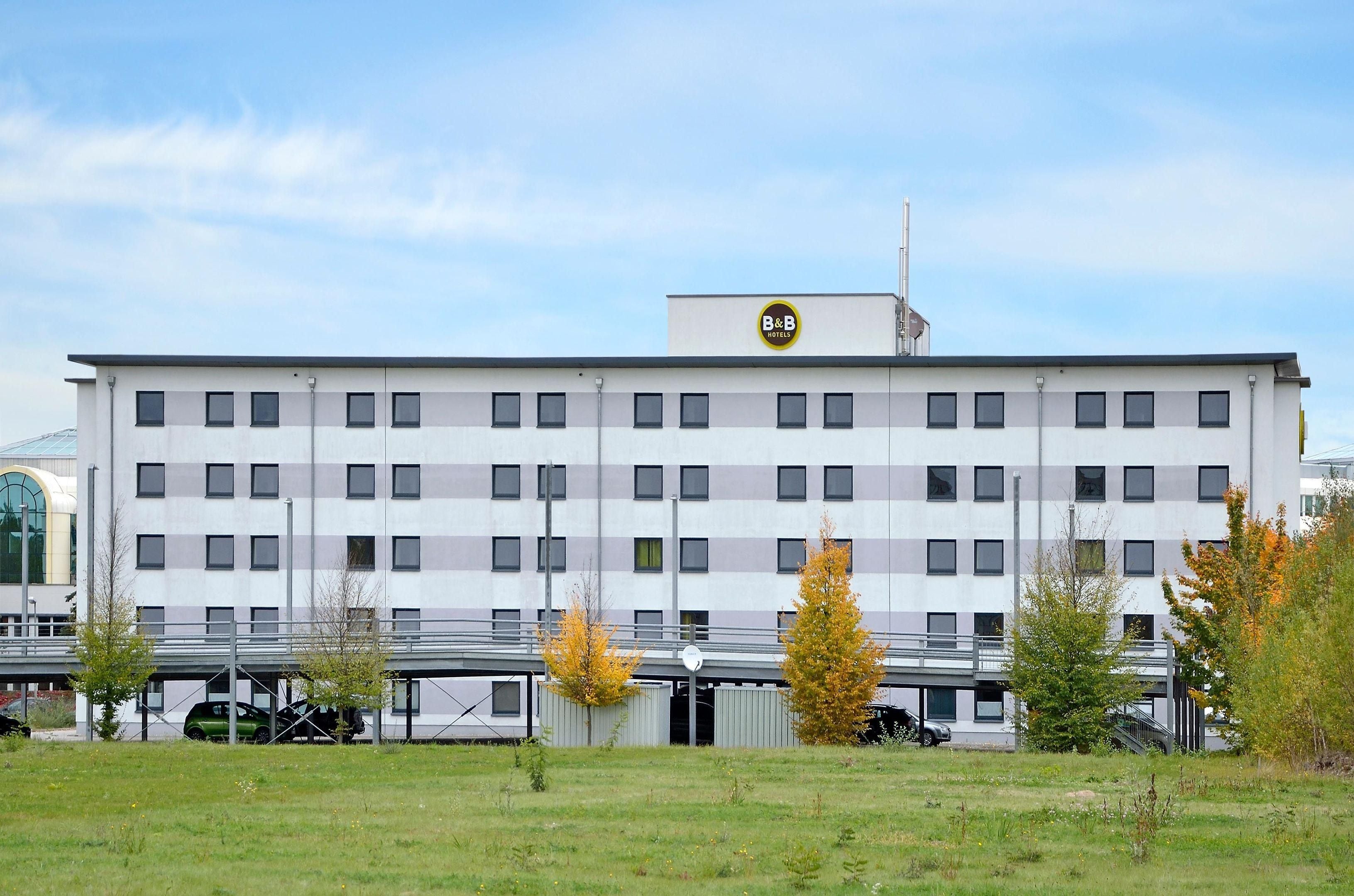 A modern hotel building with a flat roof, multiple windows, and a sign indicating it is a B&B.