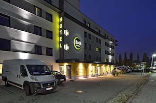 Een modern hotelgebouw met een bord waarop 'B&B Hotels' staat en een parkeerplaats met verschillende voertuigen.