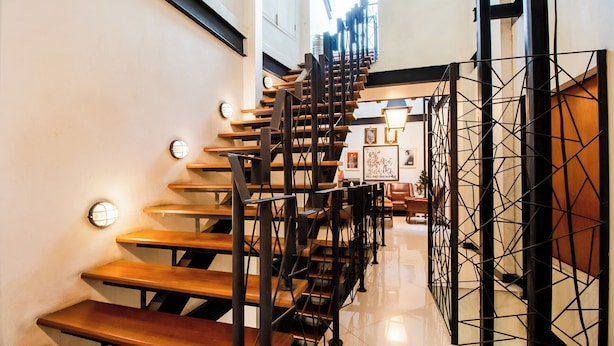 A staircase with wooden steps and black metal railings, leading to a higher floor. - The Secret Service Hotel (Bangkok)