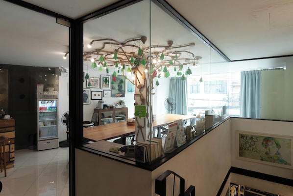 A modern interior with a glass partition, a wooden desk, and a decorative tree with hanging lights. - The Secret Service Hotel (Bangkok)