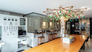 A modern kitchen with a wooden dining table, bar stools, and a decorative tree hanging from the ceiling. - The Secret Service Hotel (Bangkok)