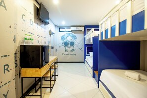 A compact hotel room with bunk beds, a TV on a wooden table, and a wall with a graphic and text. - The Secret Service Hotel (Bangkok)