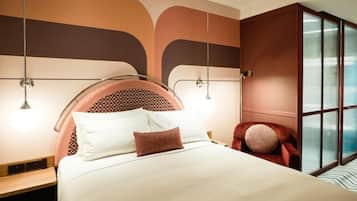 A modern hotel room with a large bed, a red armchair, and a large window with a view.