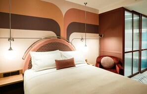 Ein modernes Hotelzimmer mit einem großen Bett, einem roten Sessel und einem großen Fenster mit Blick.