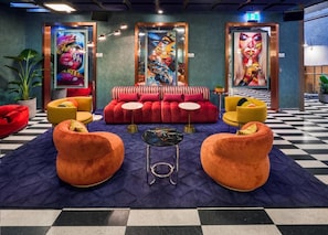 A lobby with a checkered floor, red and yellow sofas, and colorful artwork on the walls. - Ovolo Melbourne South Yarra a Wyndham Hotel (Melbourne)