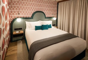 A neatly made bed with white and teal pillows, a dark headboard, and a bedside table with a lamp. - Ovolo Melbourne South Yarra a Wyndham Hotel (Melbourne)