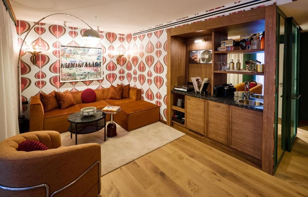 A cozy living room with a sofa, a coffee table, and a small side table. There is a kitchen area with wooden cabinets and a countertop.