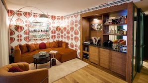 Una sala de estar acogedora con un sofá, una mesa de centro y una mesita auxiliar. Hay una zona de cocina con armarios de madera y una encimera.