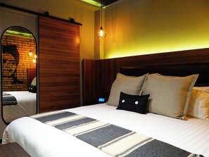 A modern hotel room with a large bed, wooden headboard, and a mirror reflecting a brick wall. - Boutique Hotel Cadillac (Mexico City)