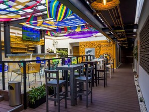 An outdoor dining area with wooden tables and chairs, a decorative ceiling, and a mural on the wall. - Boutique Hotel Cadillac (Mexico City)