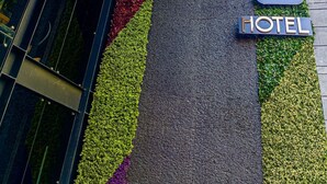 A hotel entrance with a vertical garden design, a sign reading "CADLA HOTEL", and a modern building facade. - Boutique Hotel Cadillac (Mexico City)