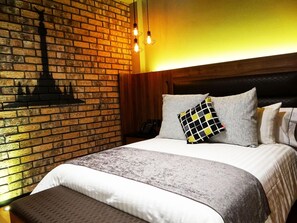 A hotel room with a brick wall, a wooden headboard, and a bed with multiple pillows. - Boutique Hotel Cadillac (Mexico City)