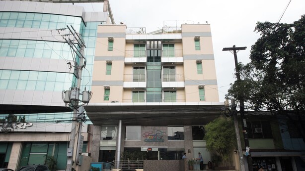 A multi-story building with a central entrance, a visible staircase, and a sign for a business establishment. - Festive Hotel Makati (Makati)