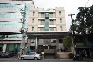 A multi-story building with a central entrance, a visible staircase, and a sign for a business establishment. - Festive Hotel Makati (Makati)