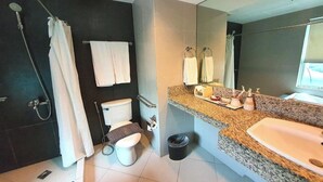 A modern bathroom with a shower, toilet, sink, and large mirror. - Festive Hotel Makati (Makati)