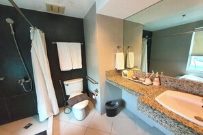 A modern bathroom with a shower, toilet, sink, and large mirror. - Festive Hotel Makati (Makati)