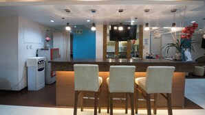 A modern hotel lobby with a reception desk, seating area, and a television. - Festive Hotel Makati (Makati)