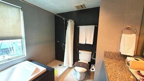 A modern bathroom with a bathtub, toilet, and sink. - Festive Hotel Makati (Makati)
