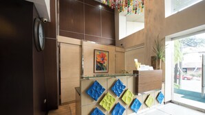 A reception area with a wooden reception desk, a clock, and a framed artwork. - Festive Hotel Makati (Makati)