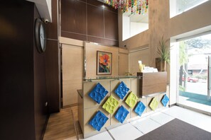 Un espace d’accueil avec un comptoir en bois, une horloge et une œuvre d’art encadrée.
