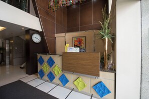 A reception area with a wooden reception desk, a clock, and a plant.