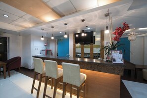 Um hall de hotel moderno com balcão de recepção, área de bar e assentos.