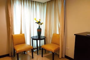 A room with two yellow chairs around a small table with a vase of yellow flowers. - Festive Hotel Makati (Makati)