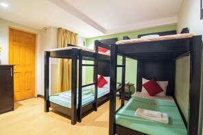 Une pièce avec des lits superposés, une porte en bois, une petite table et un mur vert.
