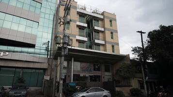 A multi-story building with a ground-level commercial space, a visible staircase, and a parked car.