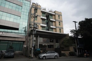 Un edificio a più piani con un locale commerciale al piano terra, una scala in vista e un'auto parcheggiata.