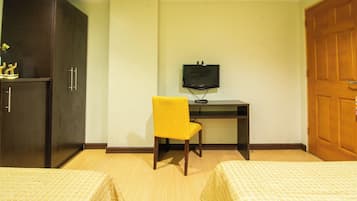 Een hotelkamer met twee bedden, een bureau met een televisie, een kledingkast en een gele stoel.