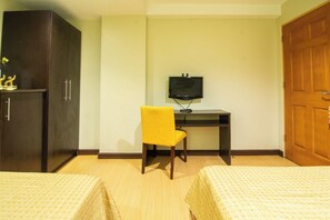 A hotel room with two beds, a desk with a television, a wardrobe, and a yellow chair. - Festive Hotel Makati (Makati)