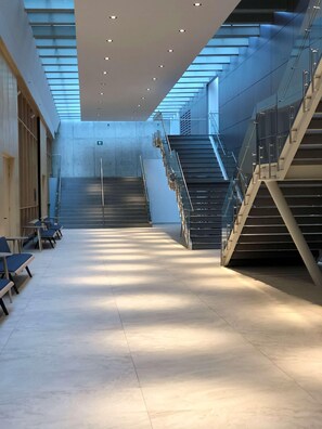 A spacious interior with a central staircase, seating area, and a skylight. - Galeria Plaza San Jeronimo (Mexico City)